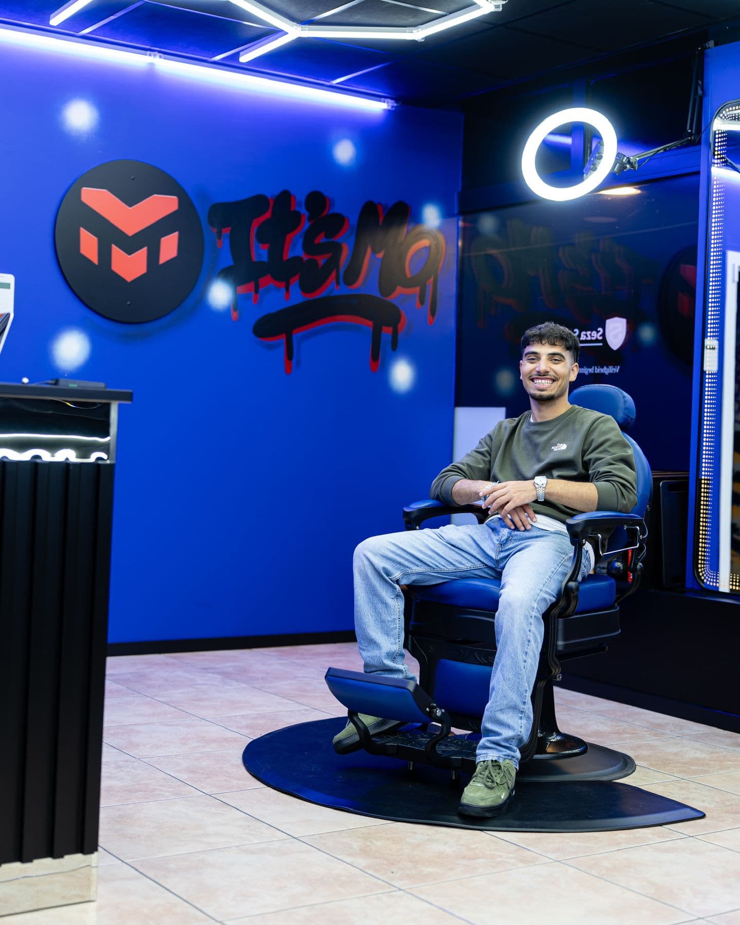 Mo zit in de blauwe barberstoel in zijn zaak