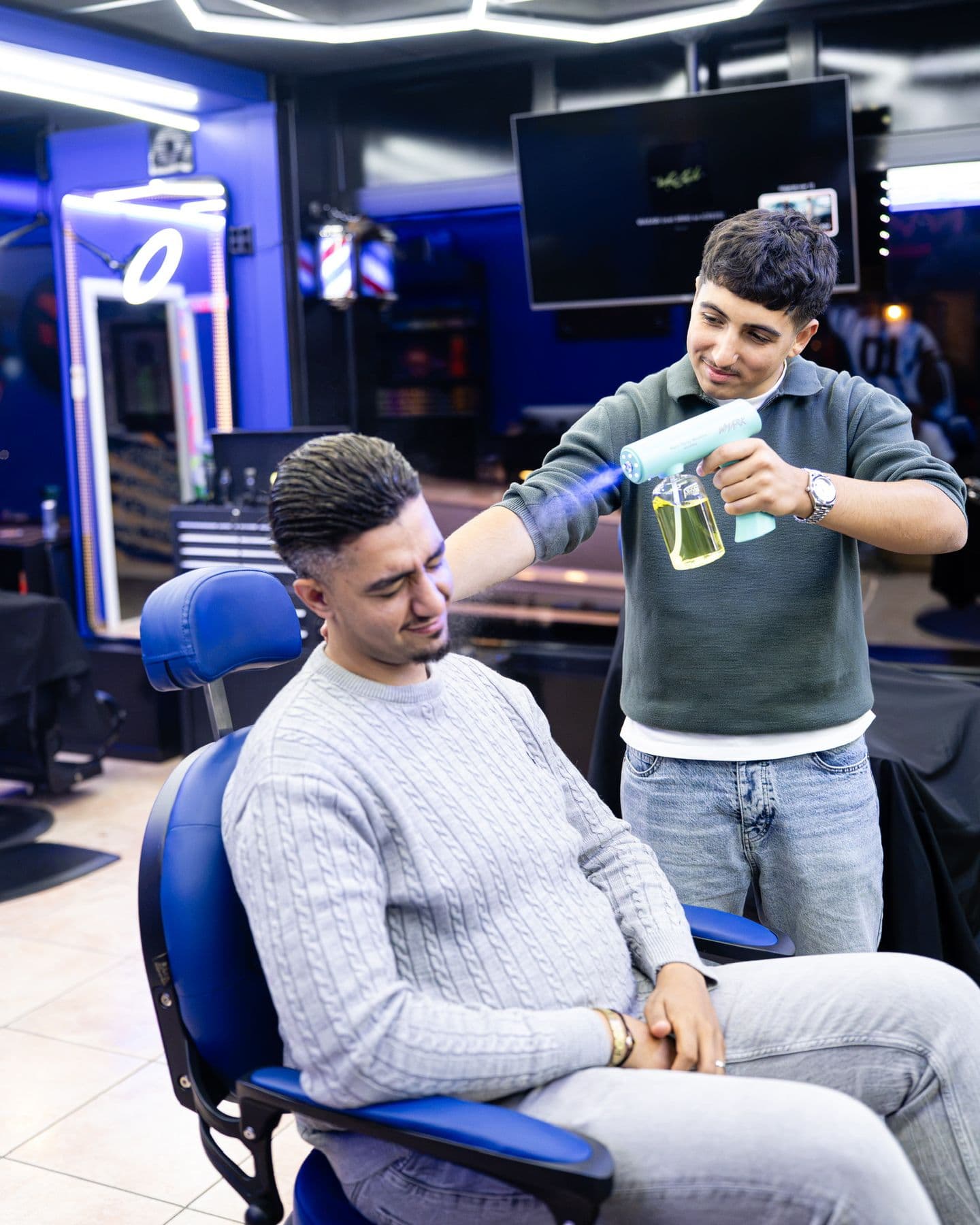 Barber sprayt water in het haar voor het stylen
