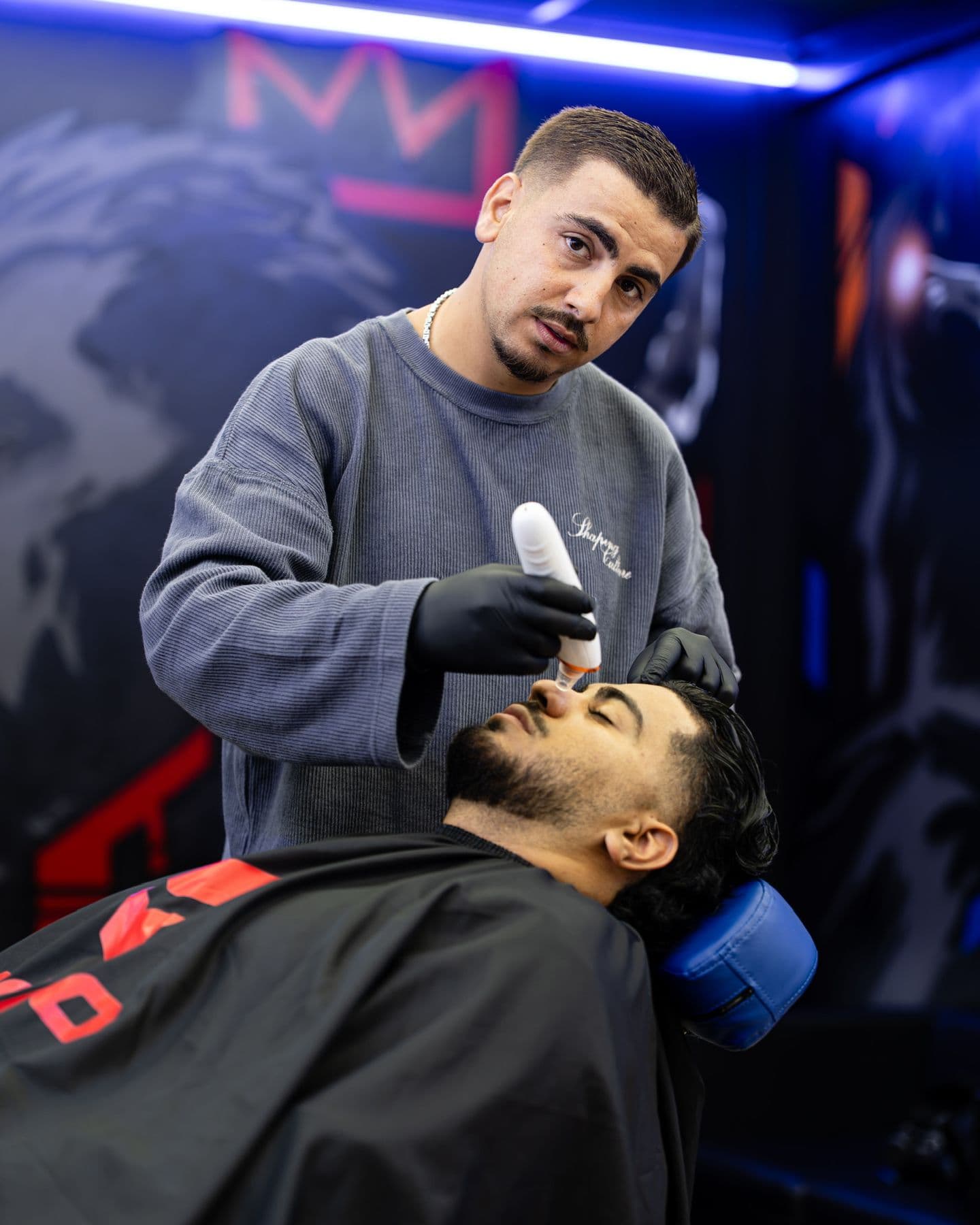Barber kijkt in de camera terwijl hij een baard trimt